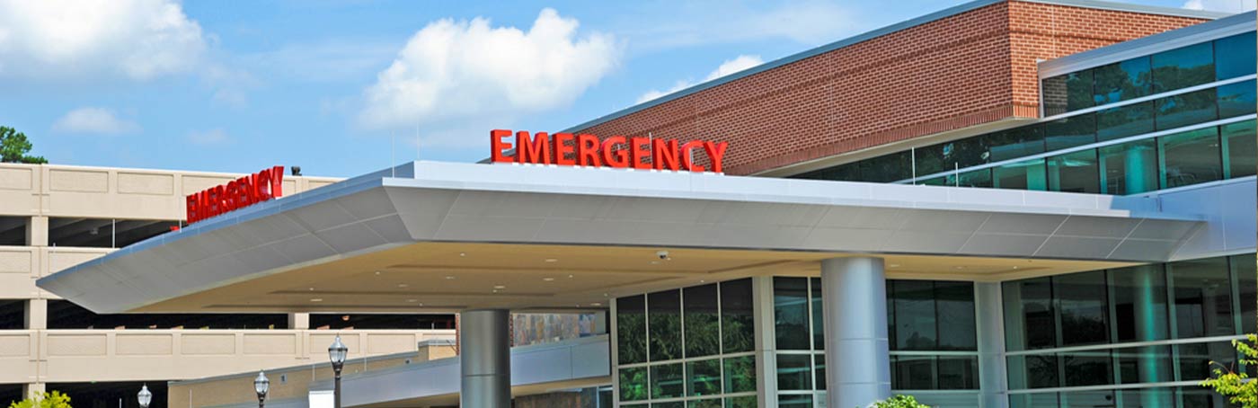 A picture of the outside of a healthcare facility, with an emergency sign on the top of the walk-in roof