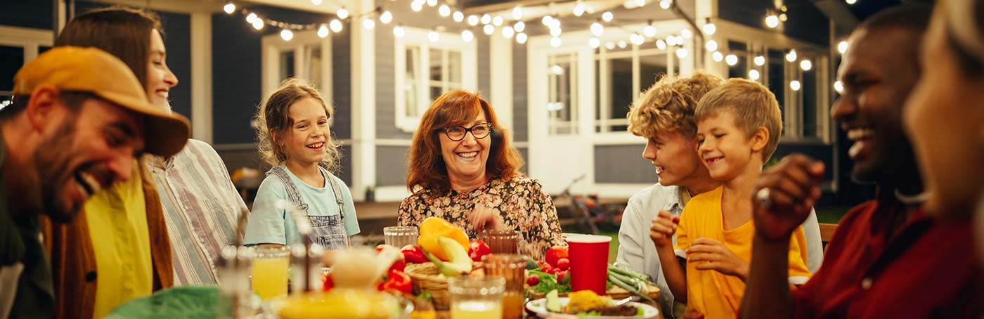 A group of family and friends laugh and enjoy a meal in the backyard