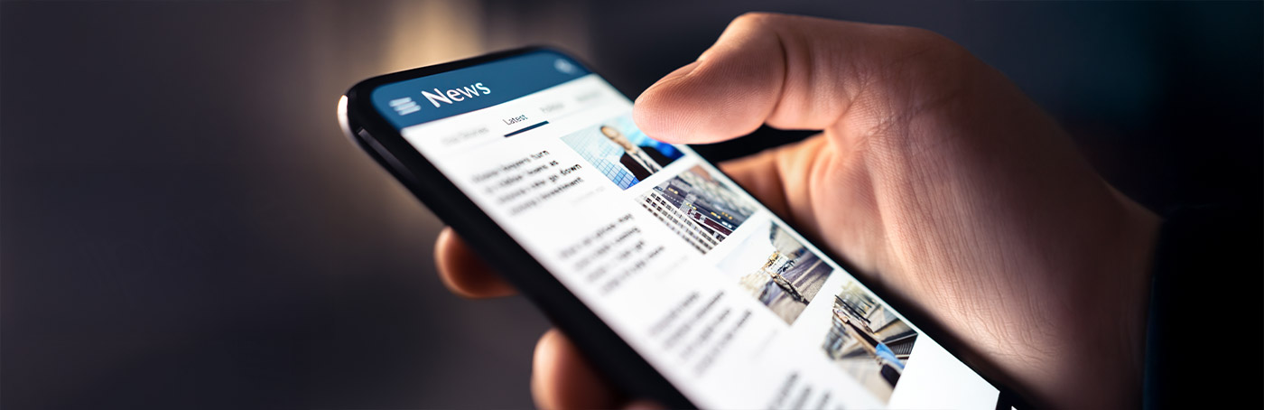 A close-up of a man holding his phone and looking up news articles