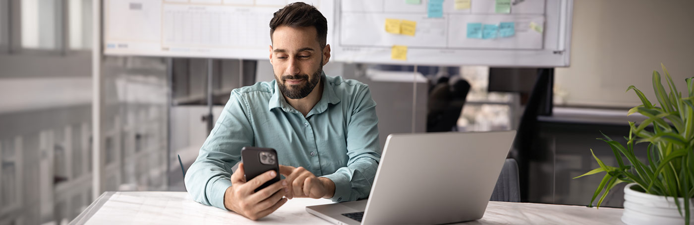 A man smiling as he is typing on his phone