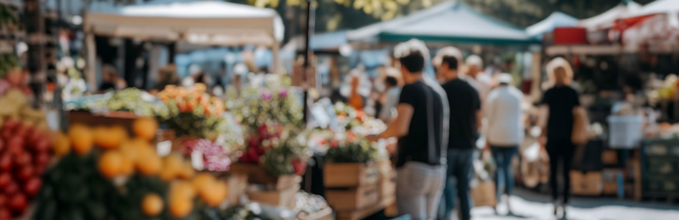 An out of focus long view image of people enjoying an outdoor farmers market